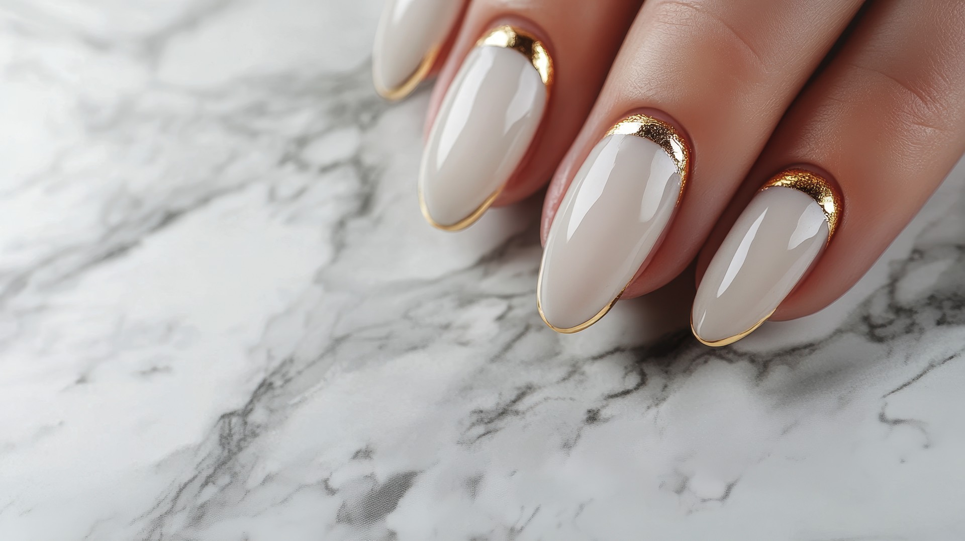 Close-up of a hand with elegant manicure featuring gold accents on a marble background. Perfect for beauty and fashion themes.